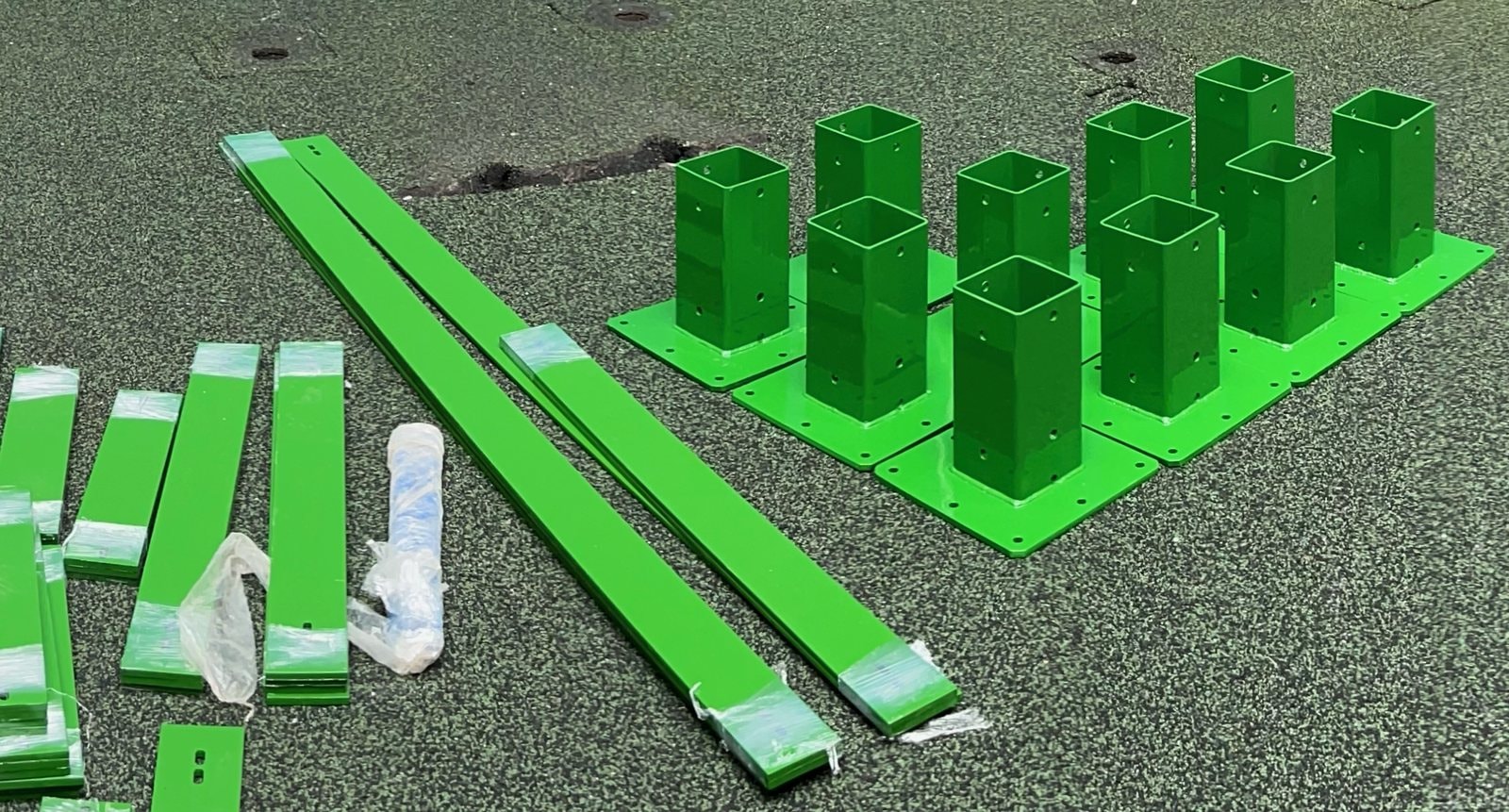 Powder-coated steel base plates and straps staged on site.