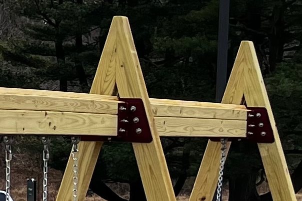 Custom powder-coated steel brackets joining an A-frame swing beam.