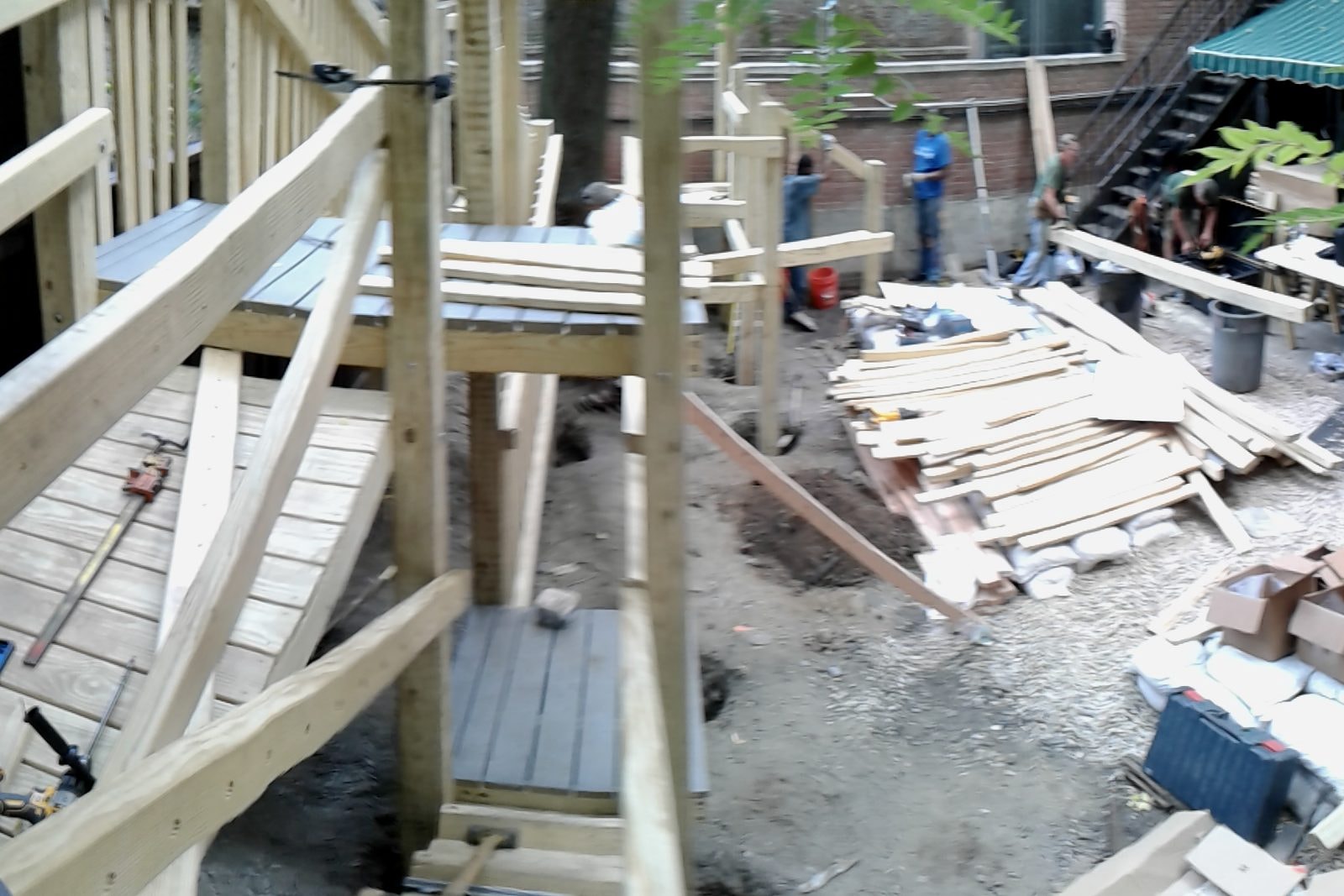 Construction: the wooden deck framing going up among stacks of lumber.