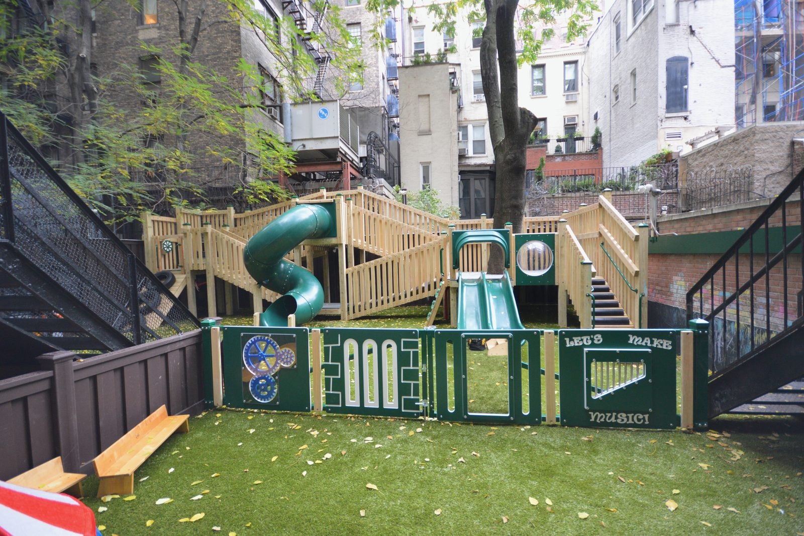 Finished: the new natural wood structure with spiral and double slides behind green activity panels.