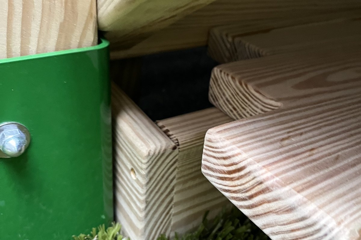 Close-up of the green post base bracket with wood stringer joinery detail.