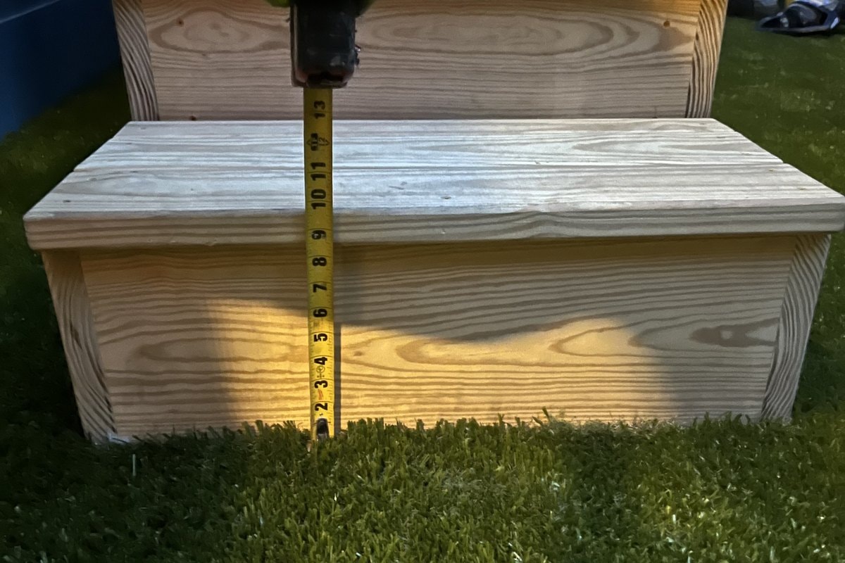 Tape measure against the bottom step riser — quality and compliance check shot.
