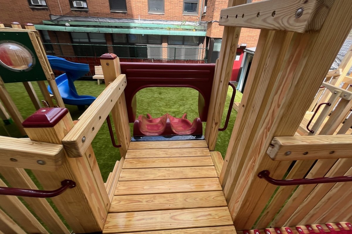 View from upper deck looking toward the slide launch — burgundy tunnel slide entry, blue spiral slide visible beyond, wood deck foreground.