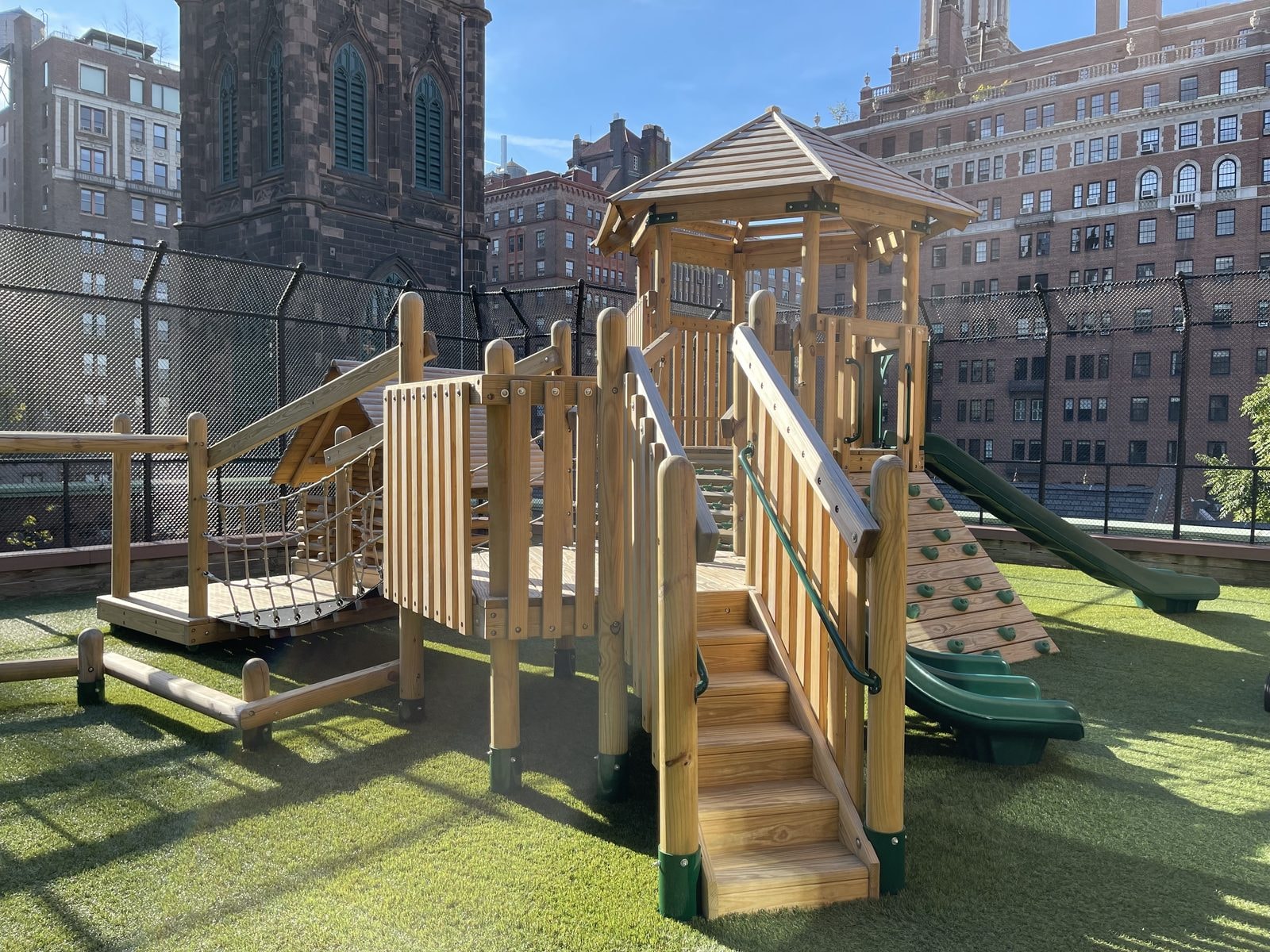 The play structure's tower and stairs with the church bell tower behind.