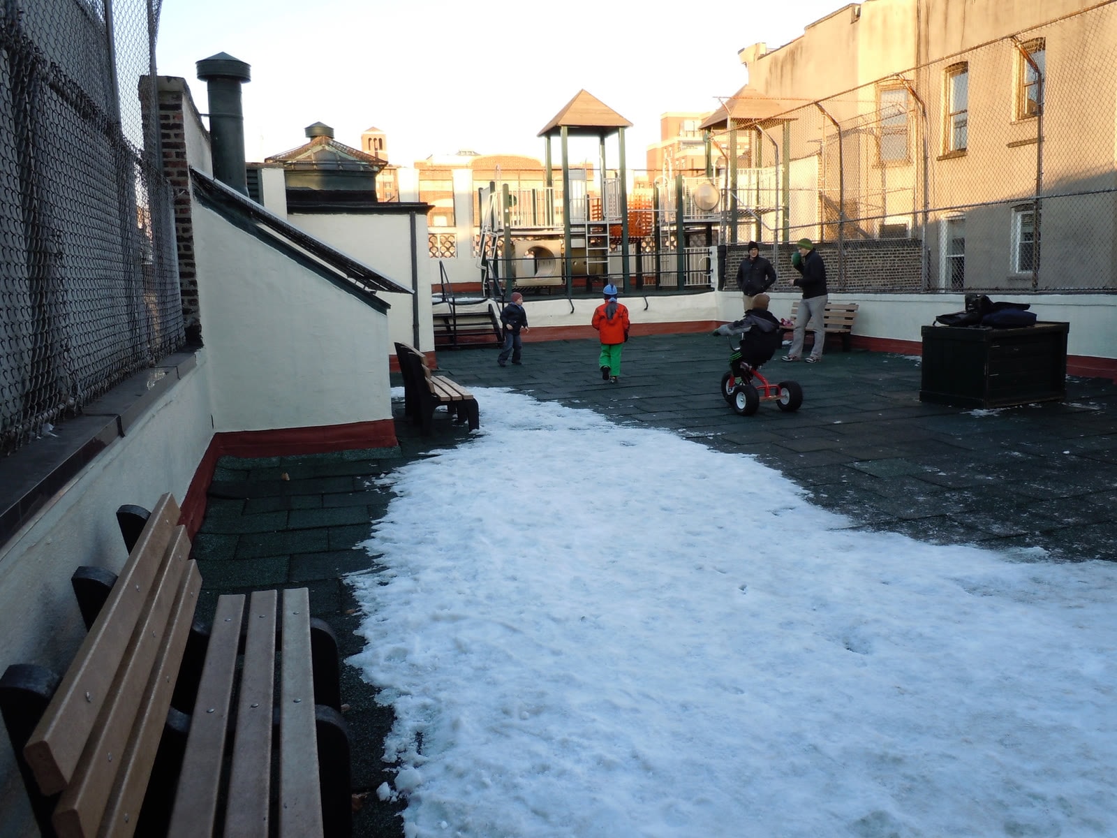 The Little Red School House rooftop before renovation — children playing in snow on the old structure.