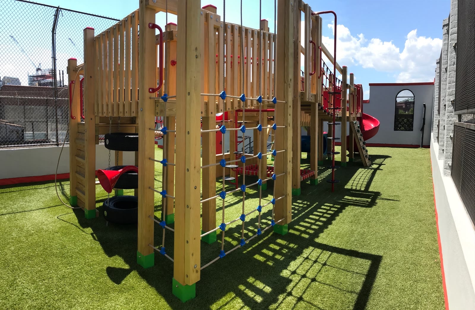 Full view of the Little Red School House rooftop play structure against a blue sky.