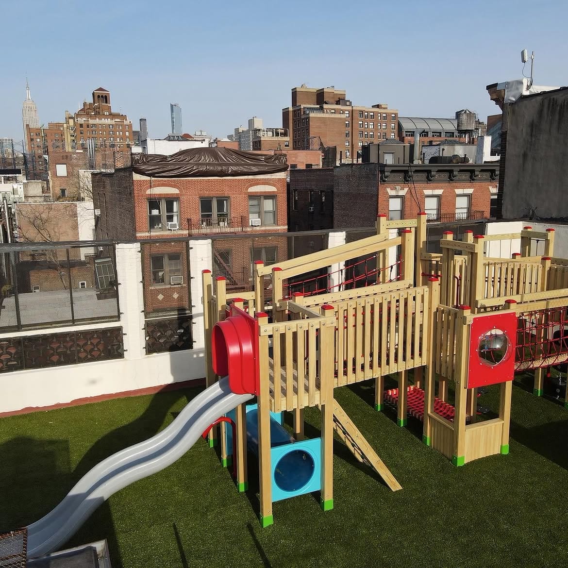 The Little Red School House play structure with the Manhattan skyline in the background.