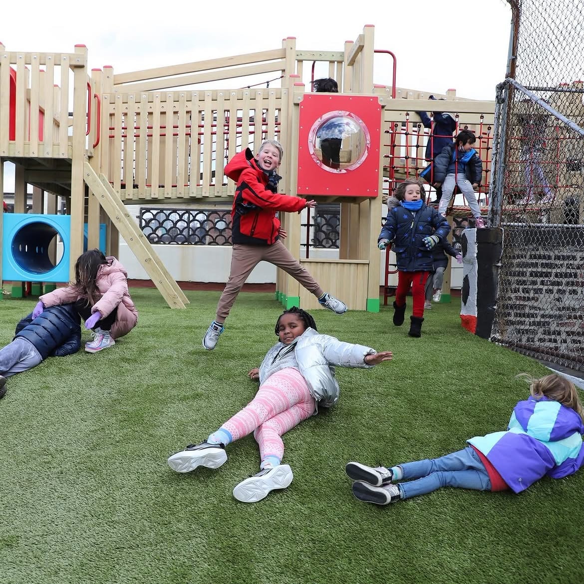 Children playing on the artificial turf of the Little Red School House rooftop playground.