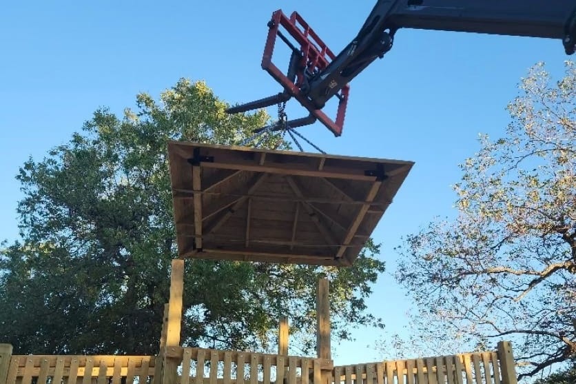 A crane lifting a roof onto a tower