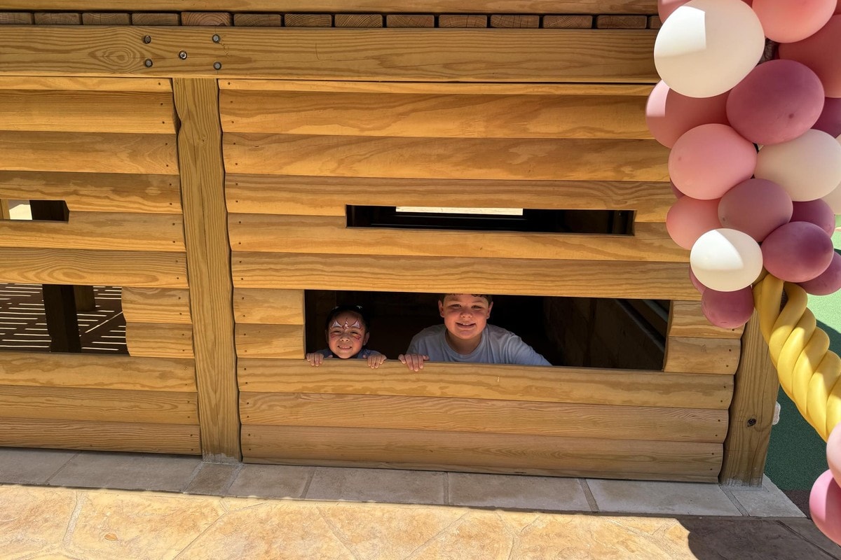 Two children looking out of a fort window