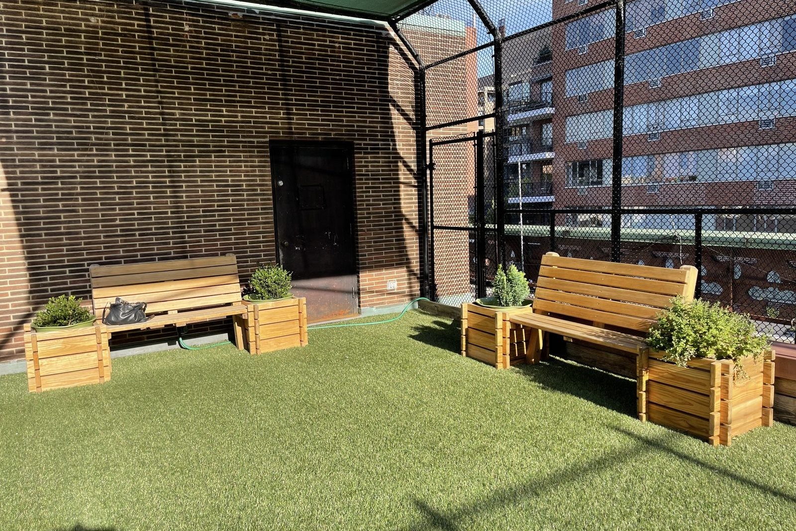 Wooden benches and planters beside a rooftop play area, where parents sit and watch.